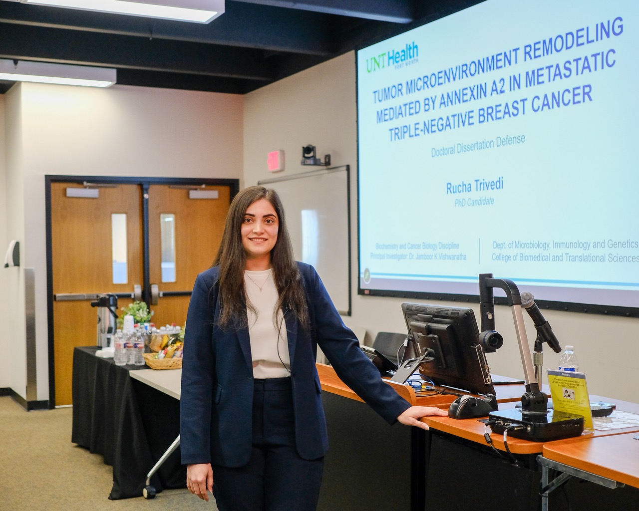 Rucha Trivedi stands in front of a presentation screen