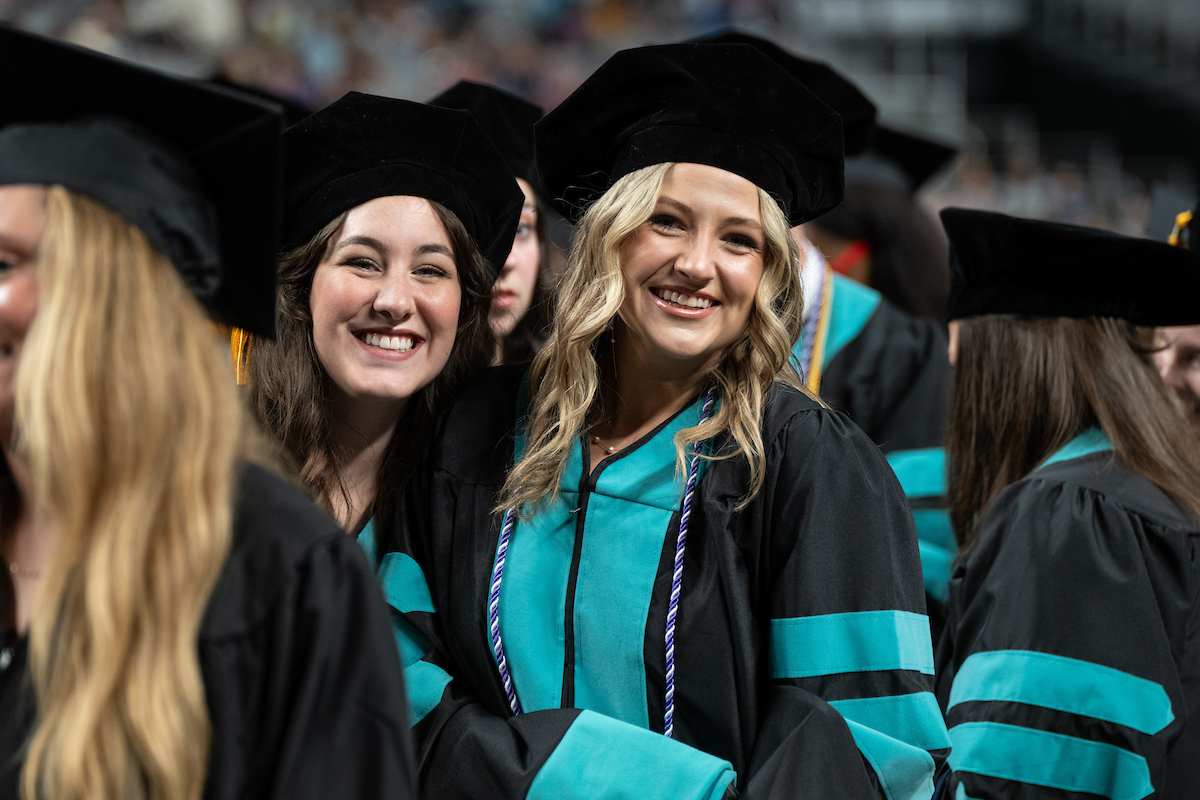 Graduates smiling while getting ready to walk across the stage