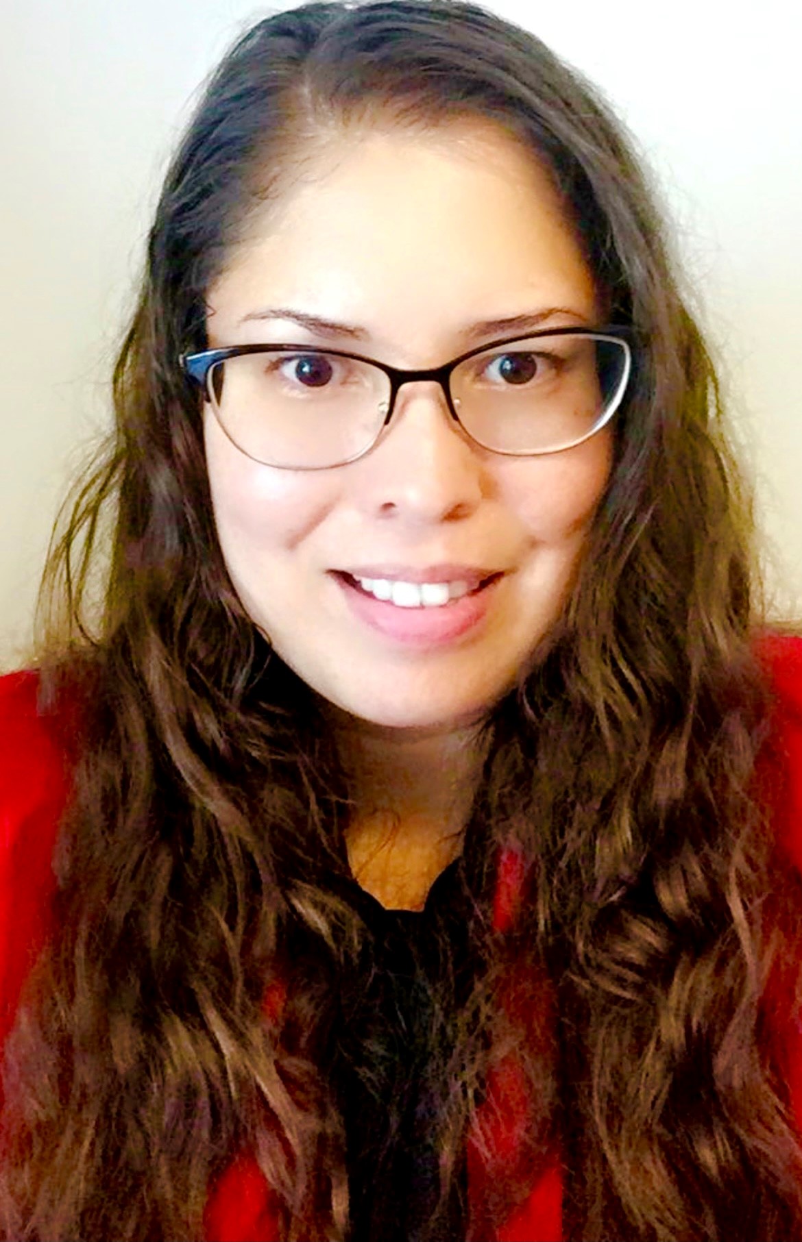 Kisna Toruno headshot wearing a red cardigan