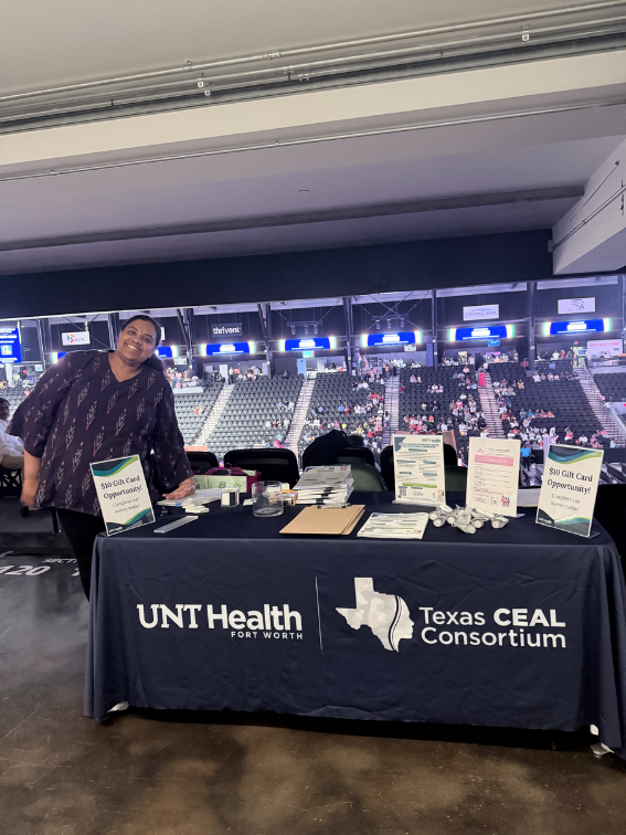 a woman standing next to a Texas CEAL branding table cloth on a table