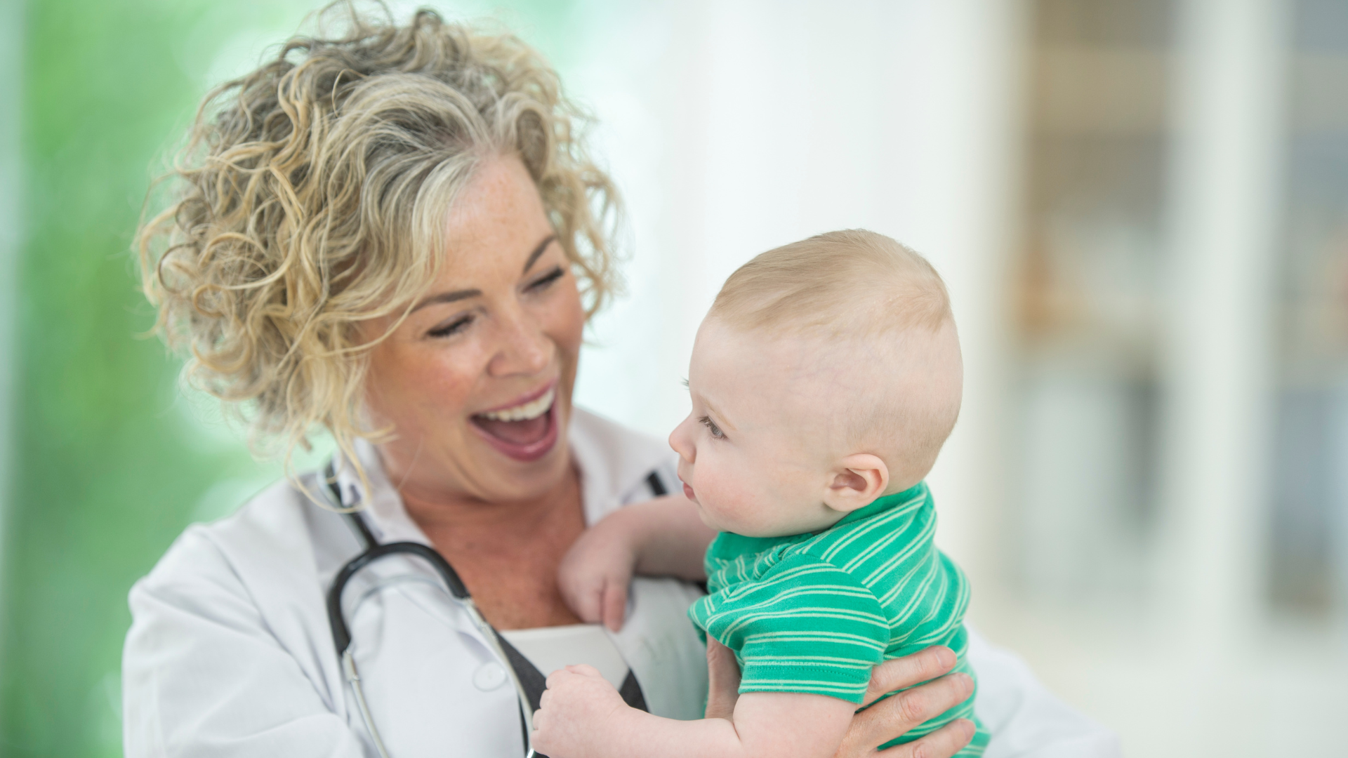 Smiling doctor holding baby