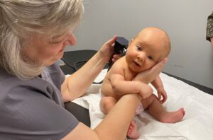 Image of doctor looking in babies ear.